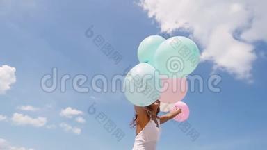 快乐美丽的女孩在海滩上跑来跑去，手里<strong>拿</strong>着<strong>气球</strong>，背景是多云的天空